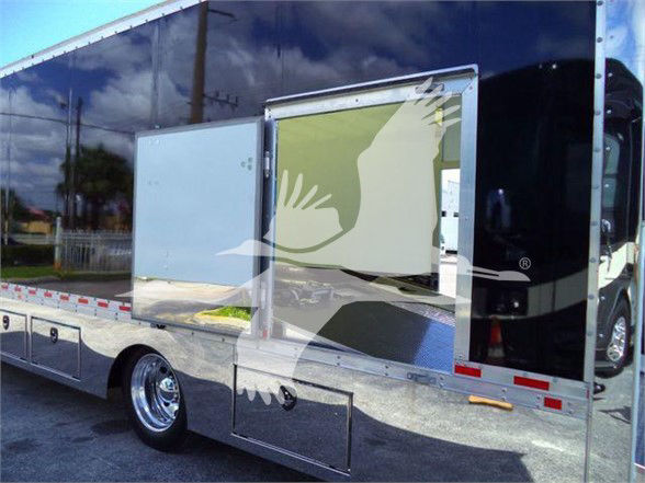 Tow truck body with open side cabinet, chrome side panels, reflective surfaces, and black cab. No legible branding or numbers visible on the image itself.