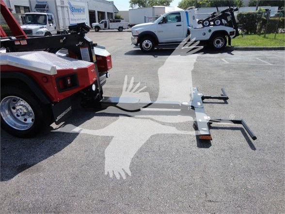 Ram 4500 tow truck with front mount hitch and flare tow equipment attached, flatbed area in a dealership lot.