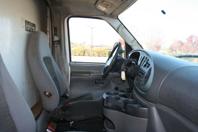 Interior of a 2005 Ford E350 van showing front seats, dashboard, steering wheel, and cup holders.