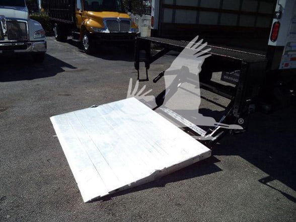 Stock image of a 2019 International DURASTAR 4300; white aluminum ramp plate in foreground; truck yard in background.