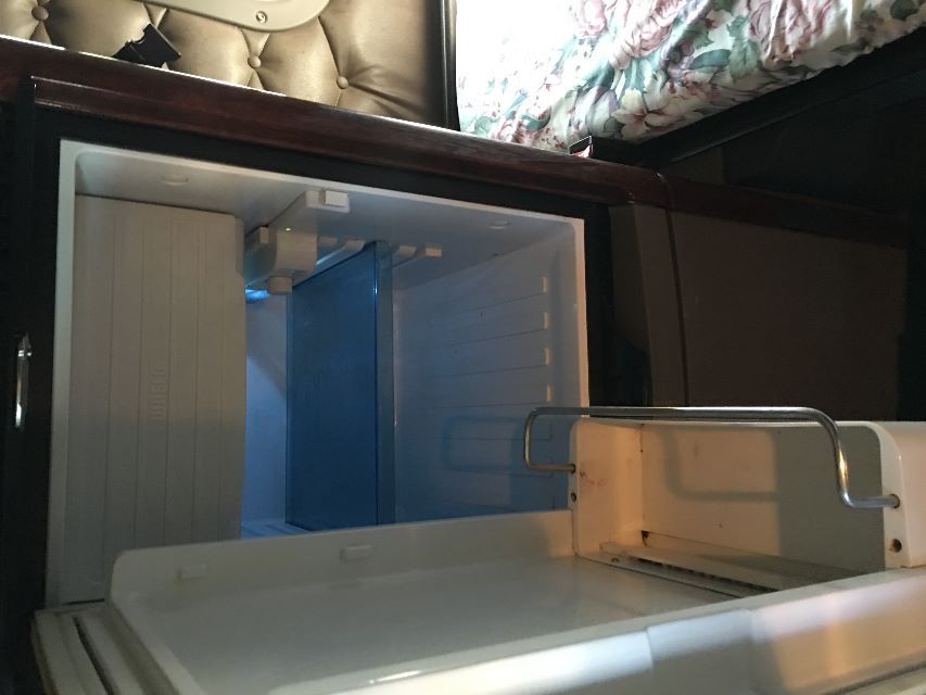 Freightliner Cascadia 125 truck cab interior with open empty refrigerator/freezer compartment visible.