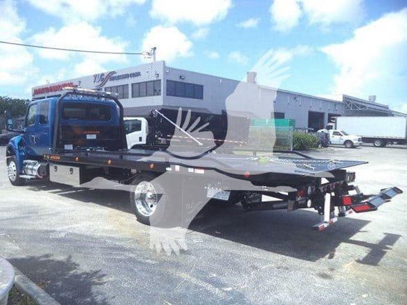 Tow truck with flatbed viewed from rear-left; International MV cab in blue, long flatbed hitch area visible.