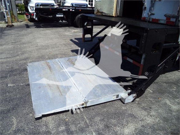 Truck trailer with aluminum loading ramp extended, visible wear lines on ramp surface.