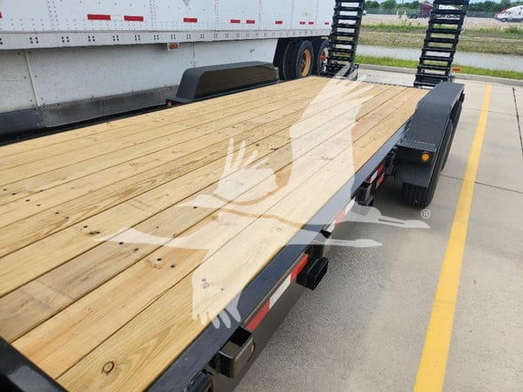 Flatbed trailer with wooden deck and dual rear ramps, view of load bed and wheel wells.