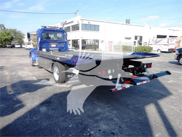 Peterbilt 337 tow truck with flatbed viewed from rear-left side showing blue cab and loading bed.