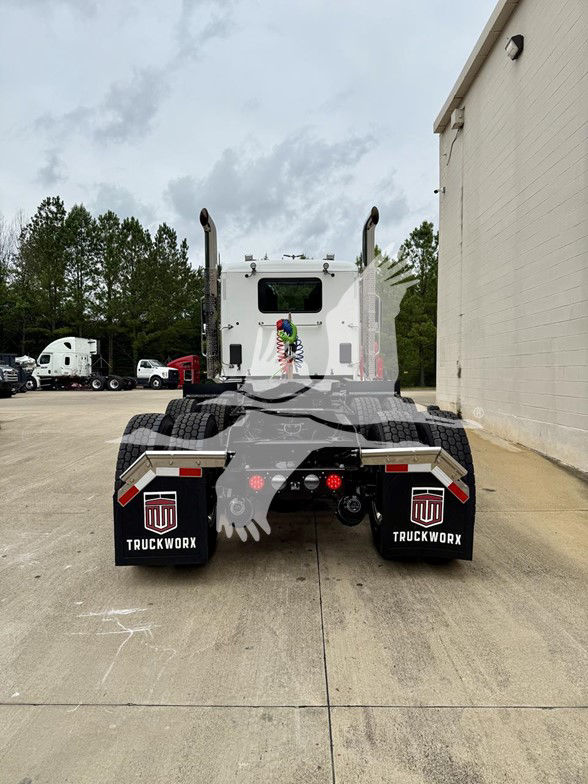 Kenworth T880 rear view showing dual rear axles, mud flaps with TruckWorx logo, and connector wiring on the back of a white cab.
