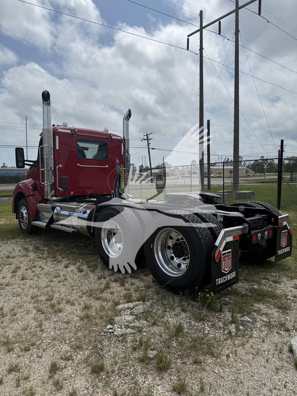 Kenworth T880 truck tractor in red, side view showing sleeper cab, chrome exhaust stacks, dual rear axles, mud flaps with TruckWork logo, and fifth wheel on a gravel lot.