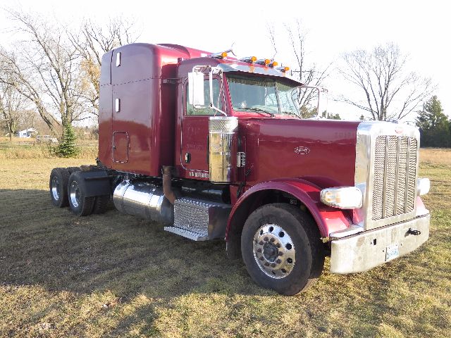 Peterbilt 388 with maroon cab and chrome grille, semi-truck tractor in a field, showing front and side view.