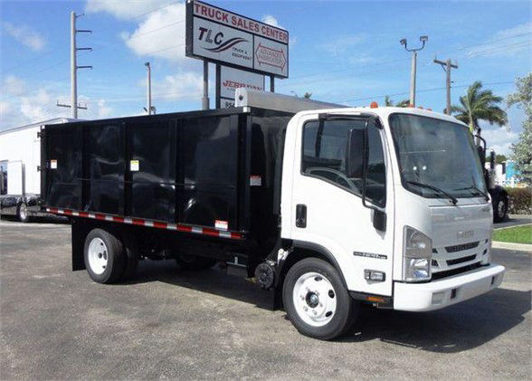Isuzu NPR HD dump truck in white cab with black dump bed, side view showing TCL Truck Sales Center sign in background.
