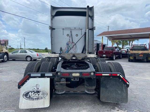 Rear view of a 2010 Mack CXU613 conventional sleeper truck showing fifth wheel, dual rear axles, and mud flaps.