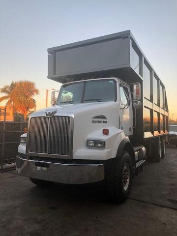 White 2012 Western Star grapple truck with front grille and large steel dump bed. visible text includes Western Star badge on grille and dump body side panels.