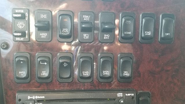 Dashboard switches and controls in a Freightliner Coronado cabin. Visible labels include WIPER, DELAY, MARKE INT, SPD CTRL, ENG BRK, DOME, ROAD LAMP, CTR, INFO, MY INFO, SHDN ON/OFF, ENG FAN, DRL DWND, etc.