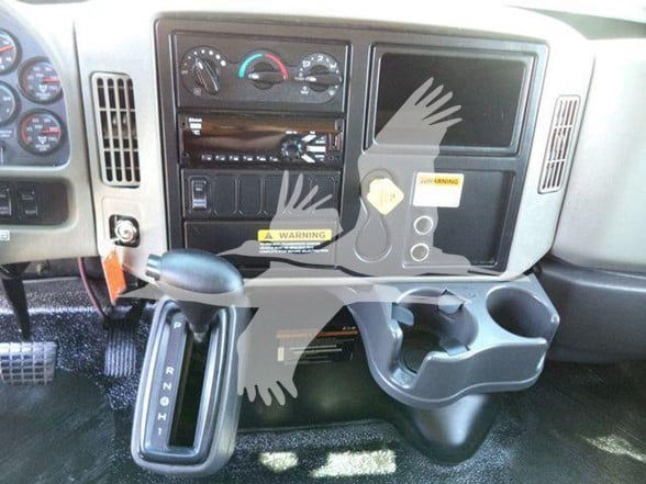 Dashboard area of a 2019 International DURASTAR 4300 with gear selector, cup holder, and control panel.