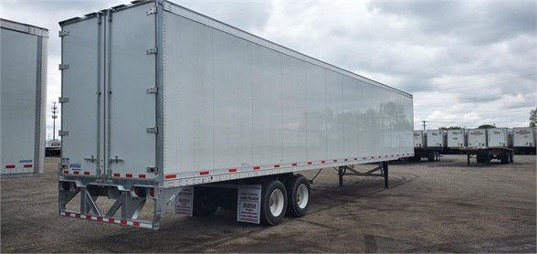 MAXCUBE dry van trailer showing long rectangular cargo box with dual rear doors and tandem axles.