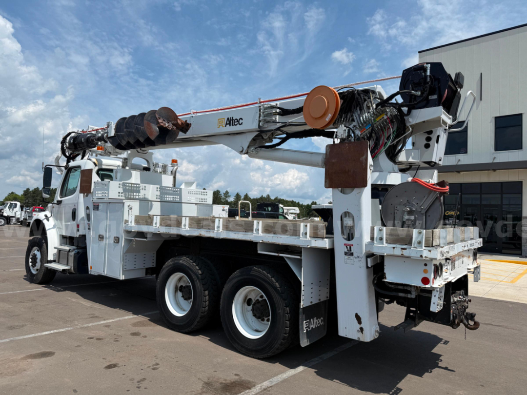 Altec DT65 derrick truck with white framework and hydraulic crane, multiple tool racks, and dual rear axles visible, showing control panels and hose reels.