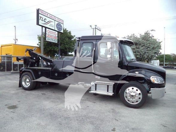 Freightliner BUSINESS CLASS M2 106 tow truck with a black cab and chrome wheels. visible text on sign: TLC Truck Sales Center, signboard in background.