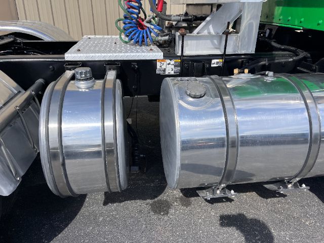 Conventional daycab truck fuel tanks and chassis area of a 2014 Kenworth T800 showing dual polished aluminum fuel tanks and part of the frame with hoses overhead.