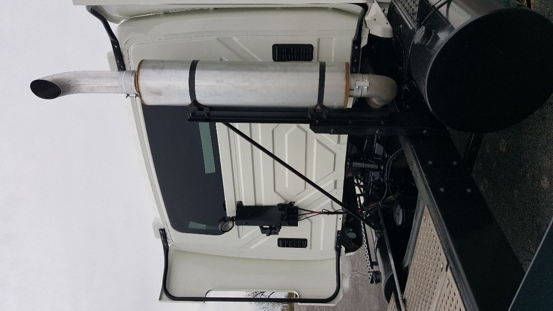 Truck exhaust stack and side cab of a 2007 International 8600 conventional daycab showing chrome vertical exhaust, white cab, and black chassis components.