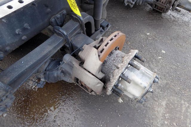 Meritor MT4014X rear axle hub and brake assembly attached to truck frame, with rust-colored rotor, dust, and surrounding components.