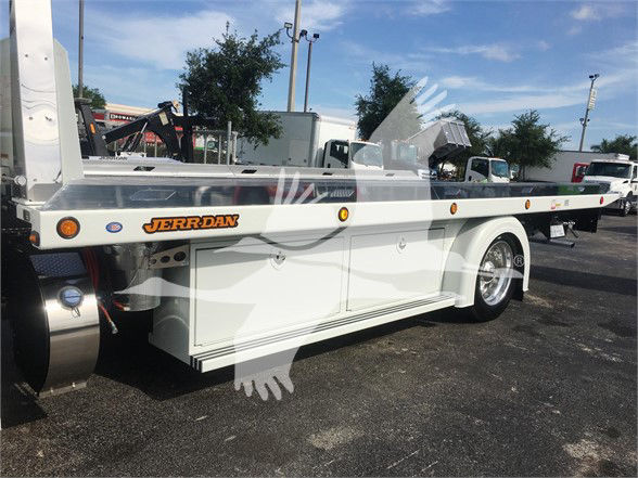 Tow truck flatbed showing JERR-DAN logo on side near front wheel and various compartments along the bed; Peterbilt 337 in background.