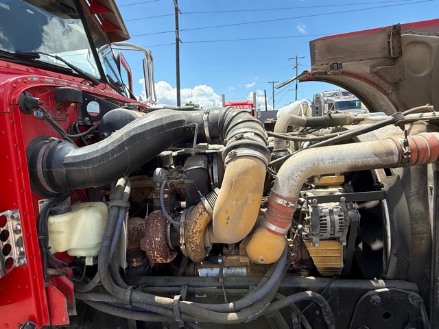 Peterbilt engine bay with multiple hoses and turbo components visible; air intake tubing and alternator present in view.