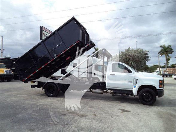 Chevrolet Silverado 6500HD dump truck in white with black dump bed raised at a used-truck lot.