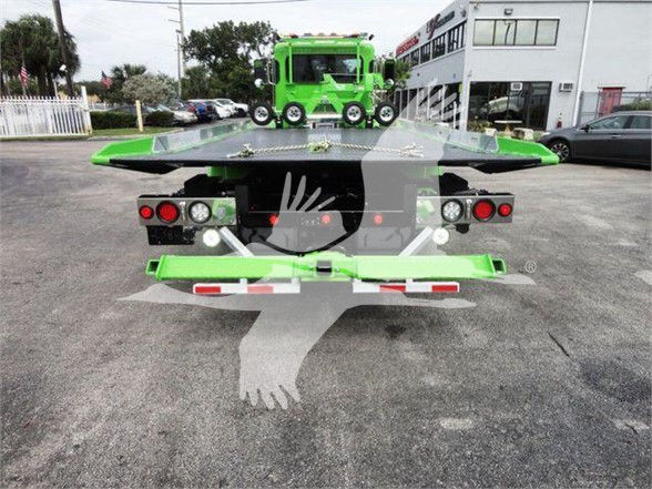 Green Peterbilt 337 tow truck rear view showing towing equipment and lights.