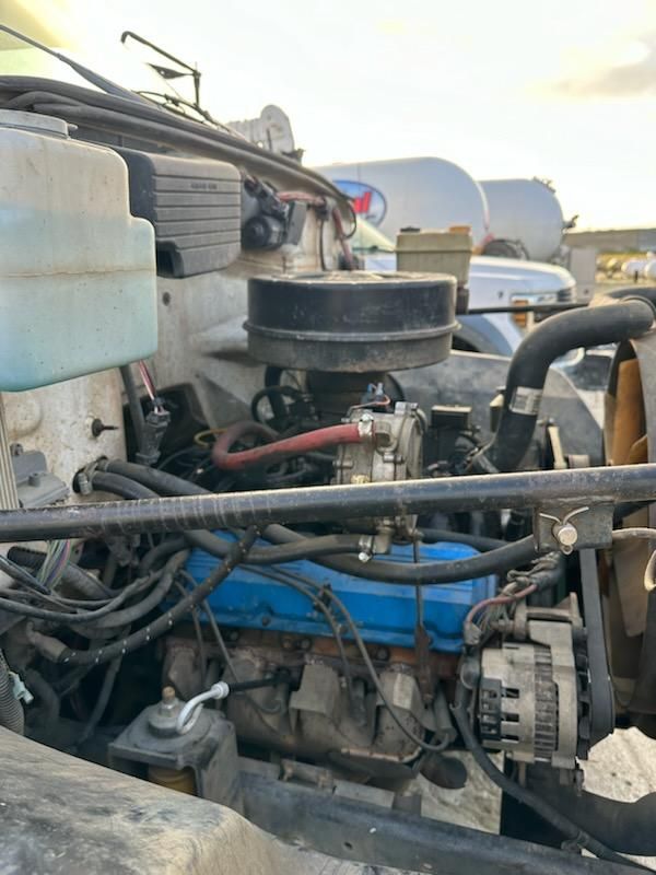 Chevrolet Kodiak 1991 engine bay showing air filter can, blue valve cover, hoses, belts, and wiring harnesses.