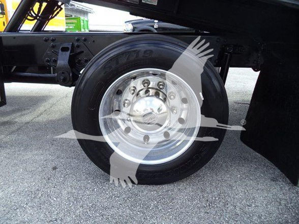 Wheel of a Hino 2014 258ALP truck showing a chrome rim and black tire with the wheel hub visible; faint background of truck frame.