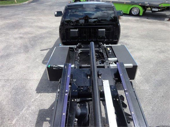 Truck bed area with a tow hitch system visible; components include rails, hydraulic or pneumatic mechanism, and control modules. No readable labels or serials clearly visible.