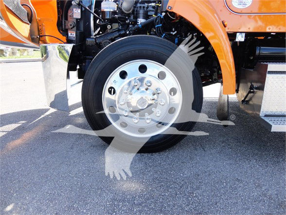 Peterbilt 337 front wheel well and chrome hub showing wheel and tire with orange truck body.