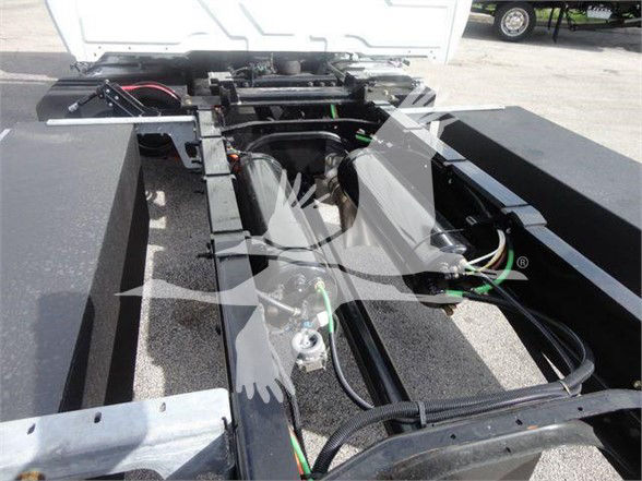  chassis frame with wiring and hydraulic lines in a truck cabless rear section; visible are green and black cables, hydraulic hoses, and metal crossmembers.