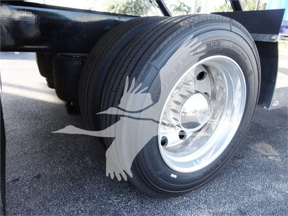 Tow truck axle/wheel with chrome rim and black tire, Peterbilt 337 framework visible in background.