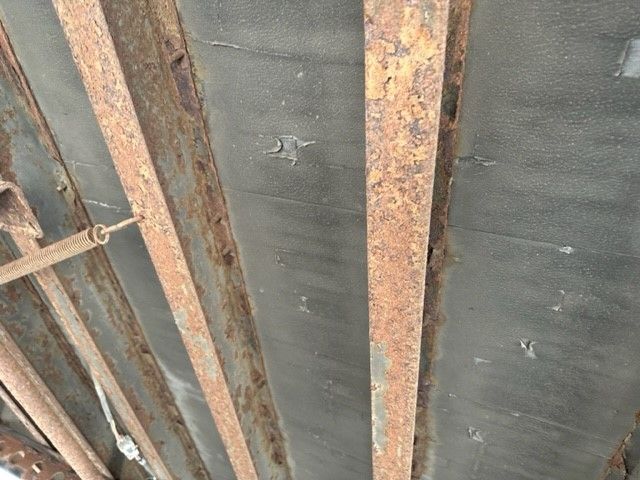 Storage trailer interior with exposed rusted steel framing and black insulated wall panels.