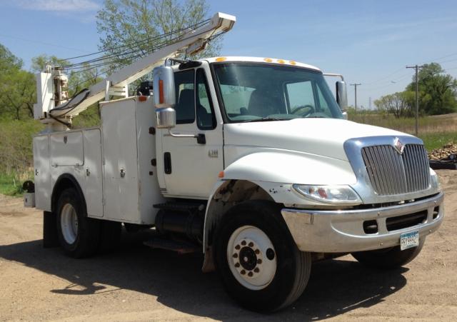 Industrial service truck with bucket lift, white cab and utility compartments, International logo visible on grille.