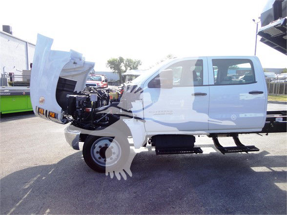 Chevrolet Silverado 5500HD cab and chassis with hood open, showing front drivetrain and chassis on a lot.