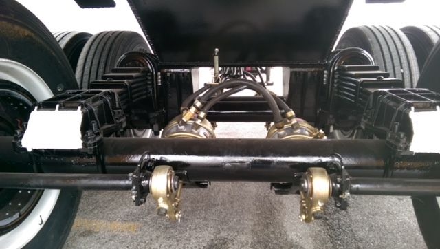 Great Dane dump trailer underside showing axles, suspension, air hoses, and center frame with dual axles and wheels.
