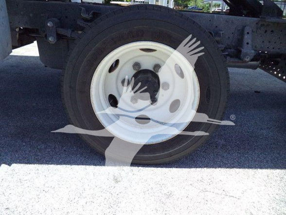 Isuzu truck wheel and chassis area with white steel wheel and tire. Some partial undercarriage visible.