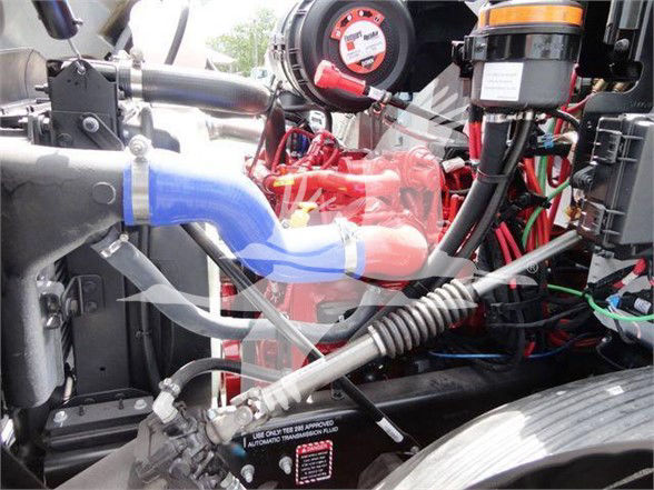Mack MD6 engine bay showing blue coolant hose, red engine components, and various wiring harnesses.