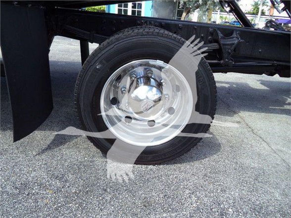 Truck wheel and chassis showing steel rim, tire, and suspension components near the underside of a 2023 International CV truck.