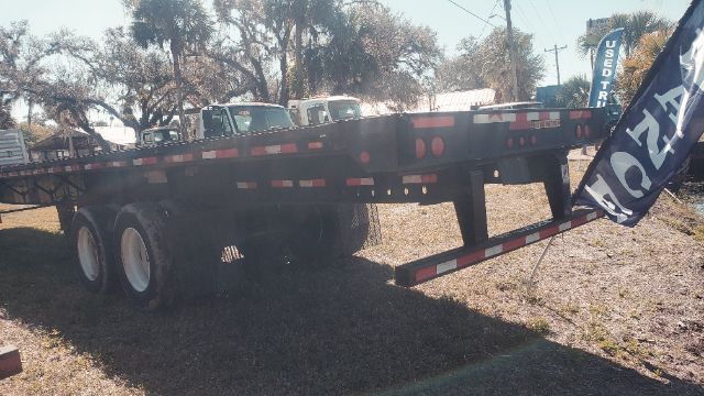 Great Dane flatbed trailer 53x102 showing dual rear axles, black-metal frame with red-and-white reflective tape and marker lights.