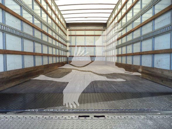Interior of a empty truck trailer with wooden wall slats and metal framing, load floor visible.