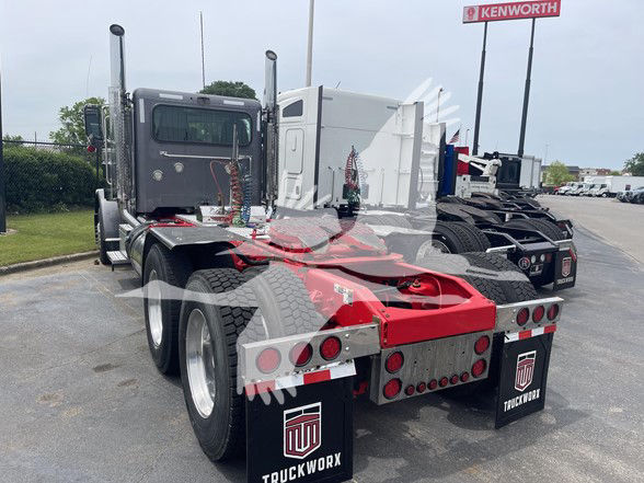 Peterbilt 389 conventional daycab tractor rear view showing dual rear axles, fifth wheel, and mud flaps with Truckworks branding.