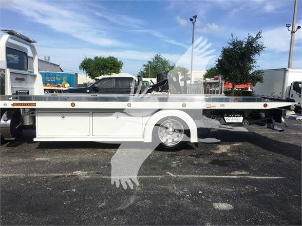Tow truck chassis with flatbed, Peterbilt 337 style, white paint, side drawers, wheel, and flatbed equipment visible.