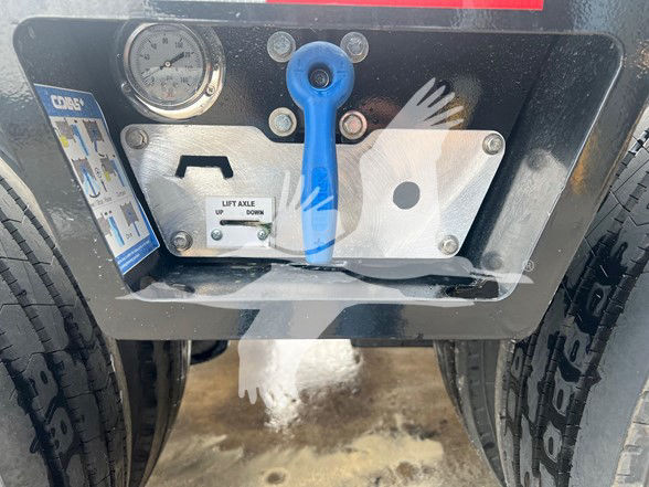 Trailer hitch control panel with blue lever, gauge, and labels. Visible text includes LIFT AXLE UP DOWN, CHCS switch labels, and various gauges and plate.