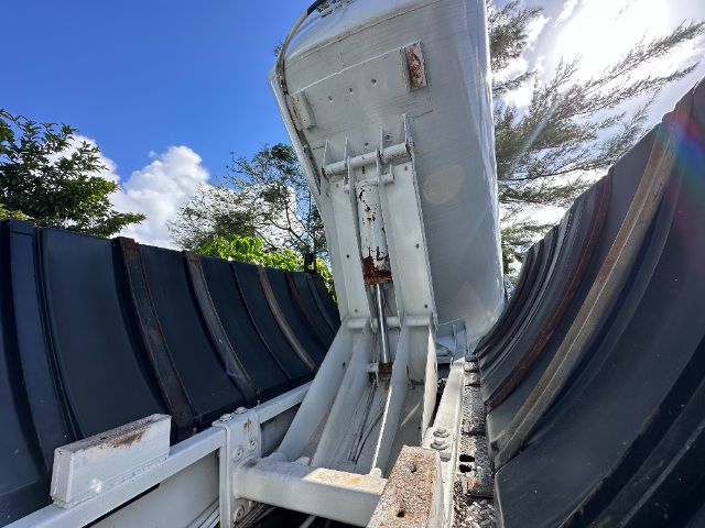 Image shows a portion of a vehicle component mounted on a truck bed with metal brackets and riveted panels, some rust and weathering visible.