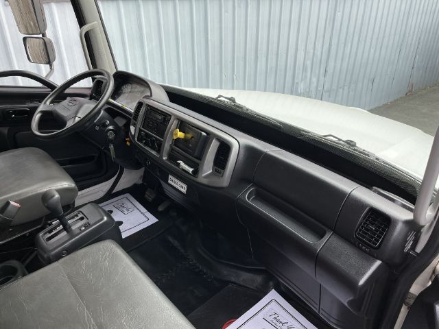 Box truck cab interior showing steering wheel, dashboard, and center console of a 2017 Hino 268. Visible paperwork on the floor and a yellow-handled lever near the center.