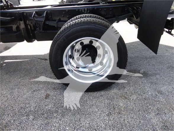 Truck wheel and suspension area of a new 2023 International CV dump truck showing a steel wheel and tire.