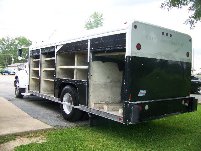 Peterbilt 335 box truck with side cargo compartments open, rear view showing black and silver exterior and empty shelves inside, gasoline/diesel vehicle.