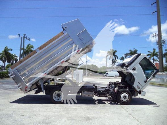 Isuzu NQR dump truck tilted with cargo bed raised, white cab, black chassis, label details not legible.